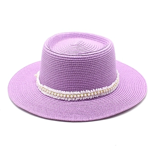 Detail view of woven purple sun hat with delicate white pearl and shell lace band trim
