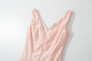 Detail of light pink V-neck dress featuring silk-like fabric and fabric-covered buttons