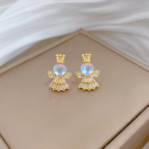 Macro detail of angel earrings with golden crown, sparkling wings and crystal dress