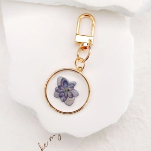 Forget-me-not dried flower keychain with purple petals in golden circular frame