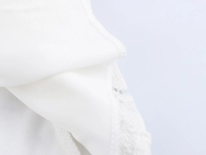 Close-up detail of white mini dress featuring delicate floral lace and soft fabric texture