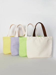 Canvas tote bags in beige, green, purple, and yellow arranged on a white background