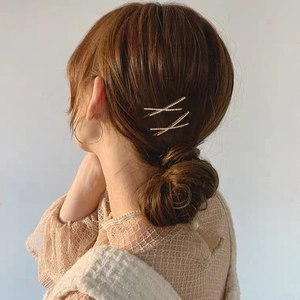 Minimalistische goldene Haarklammern mit Strasssteinen im Kreuzdesign für elegante Frisuren