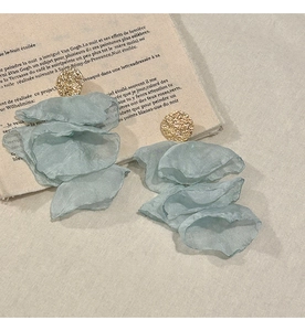 Detailed close-up of multilayered chiffon flower earrings with textured gold studs