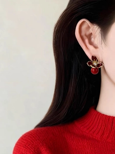 Detail of red floral earrings with gold edges and small diamonds on earlobe