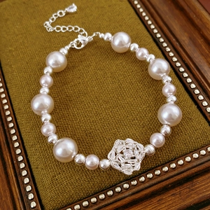 Detail of beaded pearl bracelet with zircon flower charm on olive green velvet