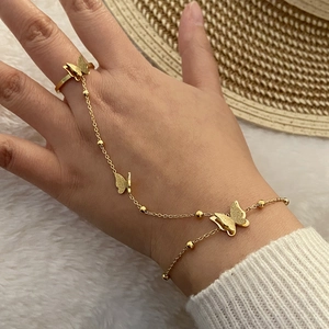 Dettaglio di un bracciale da dito dorato con ciondolo a farfalla indossato sulla mano
