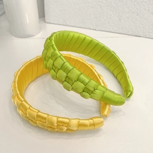 Detailed macro of handmade woven satin headbands in vibrant green and yellow colors