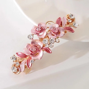 Vue macro des fleurs en émail rose et strass sur une pince à cheveux or rose