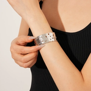 Macro detail of silver-finish wide cuff bracelet featuring hollow cutouts and hammered texture