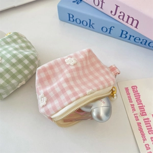 Detail of mini plaid pouch with floral lace and pearl charm holding heart-shaped earphone case