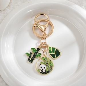 Detail of panda bamboo pendants with gold plating and green enamel on white ceramic
