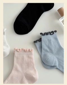 Detail of four pairs of cotton knit socks featuring ruffled edges and hollow mesh texture