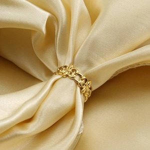Macro view of a 18K gold plated hollow chain ring displayed on elegant champagne silk