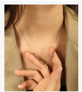 Close-up of minimalist gold beaded necklace with a sparkling zircon pendant on a model