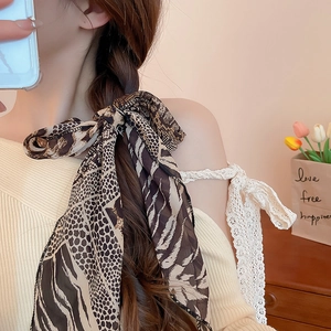 Close-up of a leopard print silk scarf used as a hair tie on a braided hairstyle