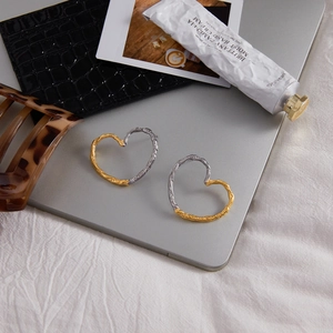 Modern two-tone heart stud earrings with unique lava texture on a minimalist lifestyle setting