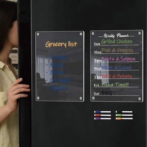 Close-up of magnetic acrylic weekly planner and grocery list boards on a fridge with markers