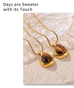 Close-up of 18k gold plated drop-shaped tiger eye stone pendants on snake chains