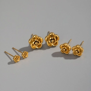 Three pairs of golden rose stud earrings in various sizes on a neutral grey background