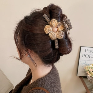 Close-up of fabric hair claw with knitted flower and check bow in soft brown tones