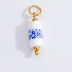 Macro detail of a cylindrical blue and white porcelain flower charm with gold clasp