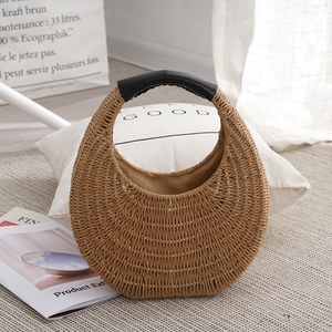Handwoven brown straw crescent bag with black leather handle in natural aesthetic