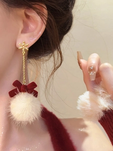 Close-up of snowflake and red bow earrings with white pom-pom on model side profile