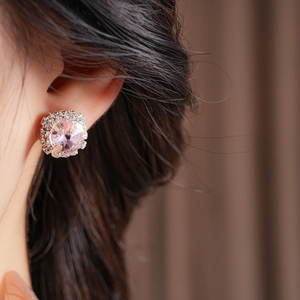 Detail shot of square pink gemstone earrings with crystal halo worn by a model