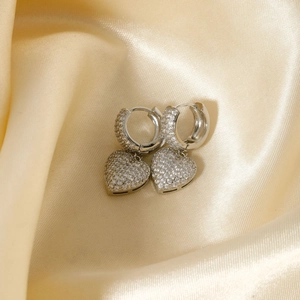 Macro shot of silver heart drop earrings with pave-set zircons on champagne silk