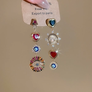 Detailed view of asymmetric earrings with Hamsa Hand, Evil Eye and red heart charms