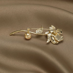 Broche élégante rose dorée avec zircon et perle sur fond en soie marron vue arrière