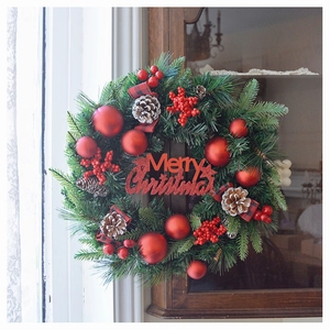 Detail eines Weihnachtskranzes mit Tannenzapfen, roten Beeren und Weihnachtsschild