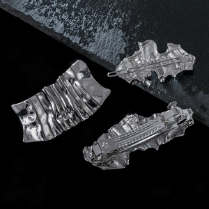 Set of silver metallic hair clips with irregular textured surfaces on black rock