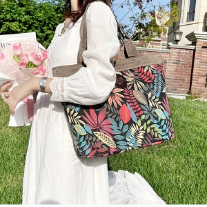 Detail of canvas tote bag with colorful tropical leaf print and wide brown handle