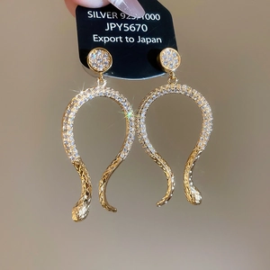 Macro view of 14k gold plated snake-shaped earrings with sparkling cubic zirconia pavé