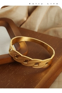 Detail view of gold titanium steel bangle showing intricate leaf texture and brushed finish