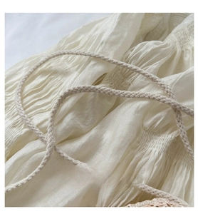Close-up of cream woven shoulder strap with detailed pleated fabric and braided cord design