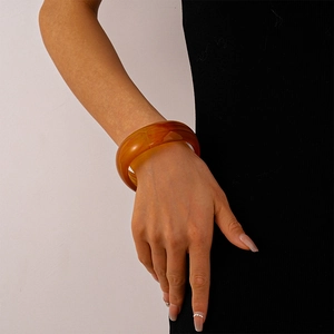 Detail of amber translucent acrylic bangle featuring a bold geometric marble texture on wrist