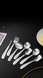 Detail of 304 stainless steel dessert spoons with engraved smile faces on black surface