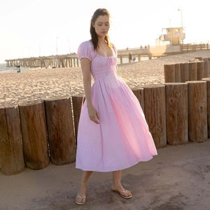 Detalle del vestido midi a cuadros rosas con mangas abullonadas y corpiño fruncido en la playa