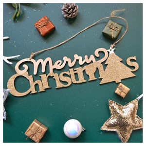 Close-up of Merry Christmas wooden pendant with gold glitter and hanging hemp rope