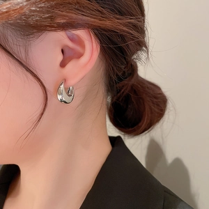 Vue rapprochée d'une boucle d'oreille géométrique en C argentée sur un mannequin en métal