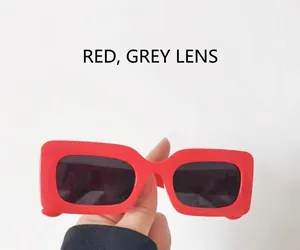 Detail view of bold red square sunglasses frame with dark gray protective lenses