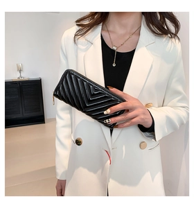 Détail du portefeuille en cuir verni noir avec matelassage en V et fermeture éclair dorée
