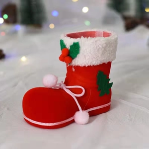Detail eines roten beflockten Weihnachtsstiefels mit Pelzbesatz und rosa Pompons
