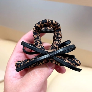 Détail de la pince à cheveux imprimé léopard avec un nœud décoratif en similicuir noir