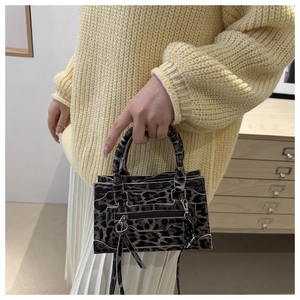 Dettaglio borsa a mano leopardata con fibbie metalliche e tracolla classica