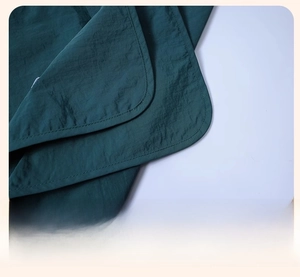 Detail of clean edge stitching and durable fabric on dark green waterproof work apron