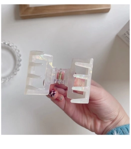 Close-up of a small square iridescent white acetate hair claw clip with a glossy finish